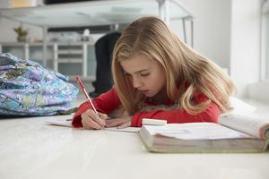 小女孩在家庭办公室的地板上做作业。