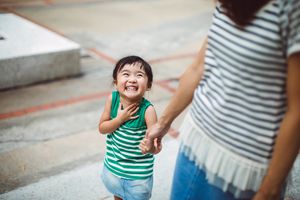 在公园里和妈妈手牵着手微笑的孩子
