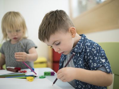 Toddler brother and sister drawing with colored pencils