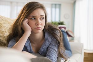 一个十几岁的女孩独自坐在沙发上。