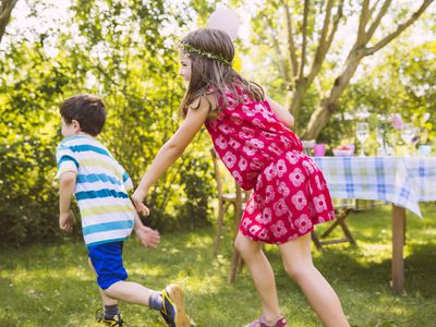 Boy and girl playing tag in garden