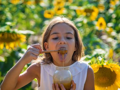 child eating honey in a field of sunflowers