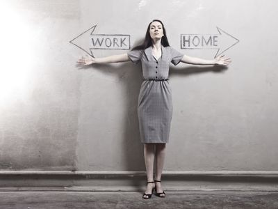 Woman standing against wall with arrows pointing in opposite directions, one says work, other says home