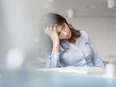 Tired businesswoman with head in hands looking away