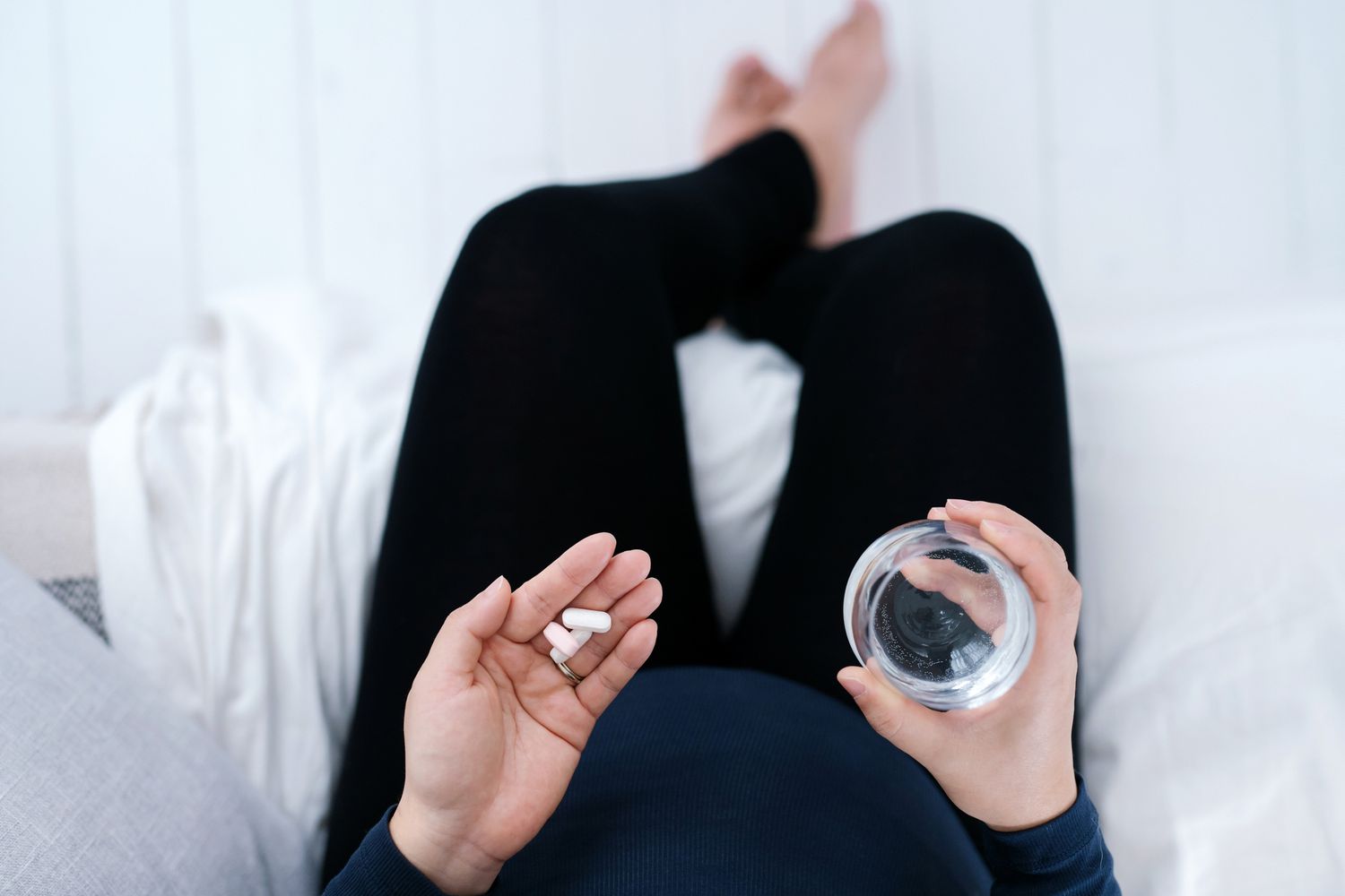 woman sitting on the bed holding vitamins in her hand
